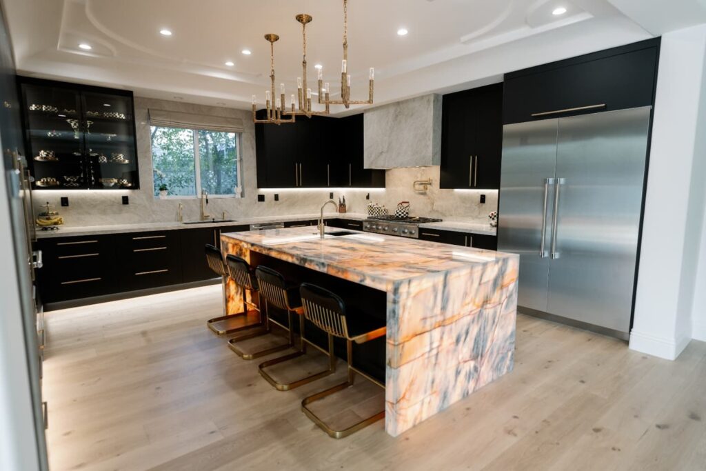 Black custom kitchen with a backlit stone waterfall island in Encino by Home Deco