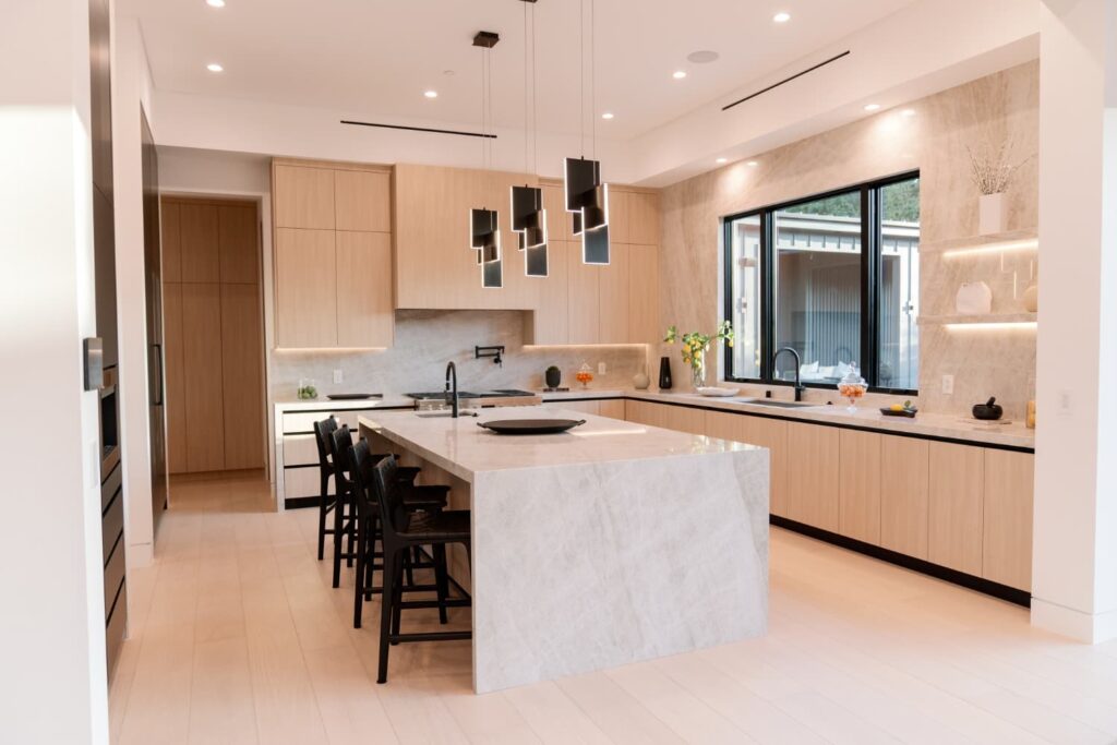 Light oak kitchen with a stone waterfall island in Woodland Hills by Home Deco