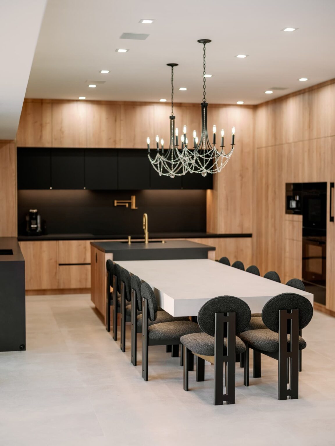 Wood and black kitchen with a chandelier above a long table in Burbank by Home Deco