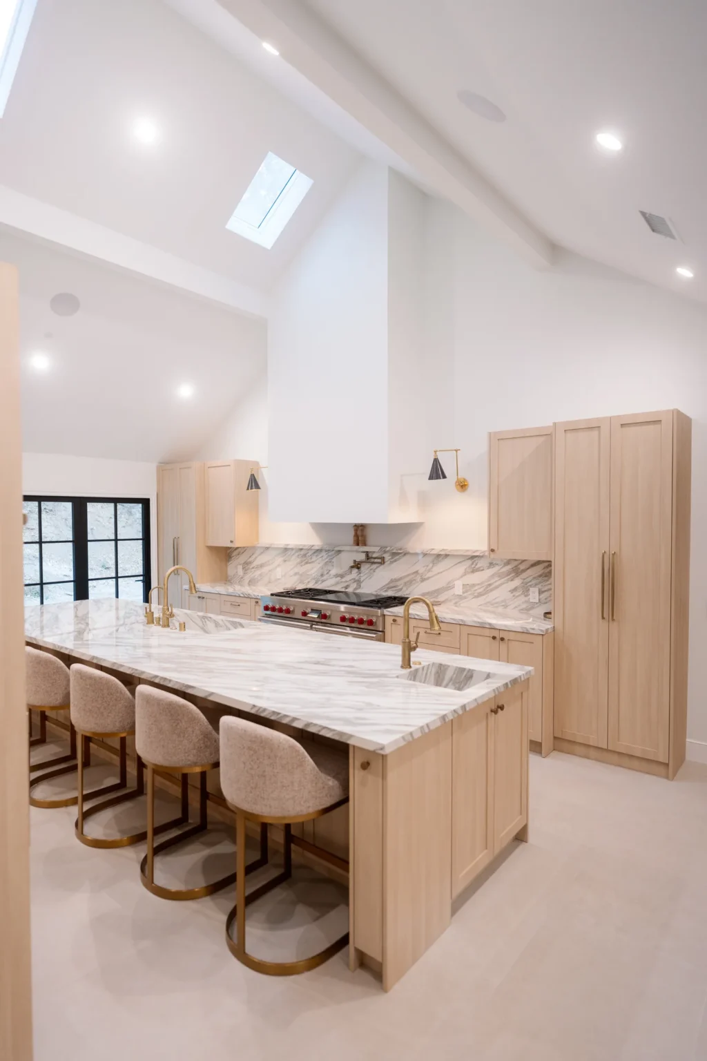Light wood shaker kitchen with a stone island under a vaulted ceiling in Bel Air by Home Deco